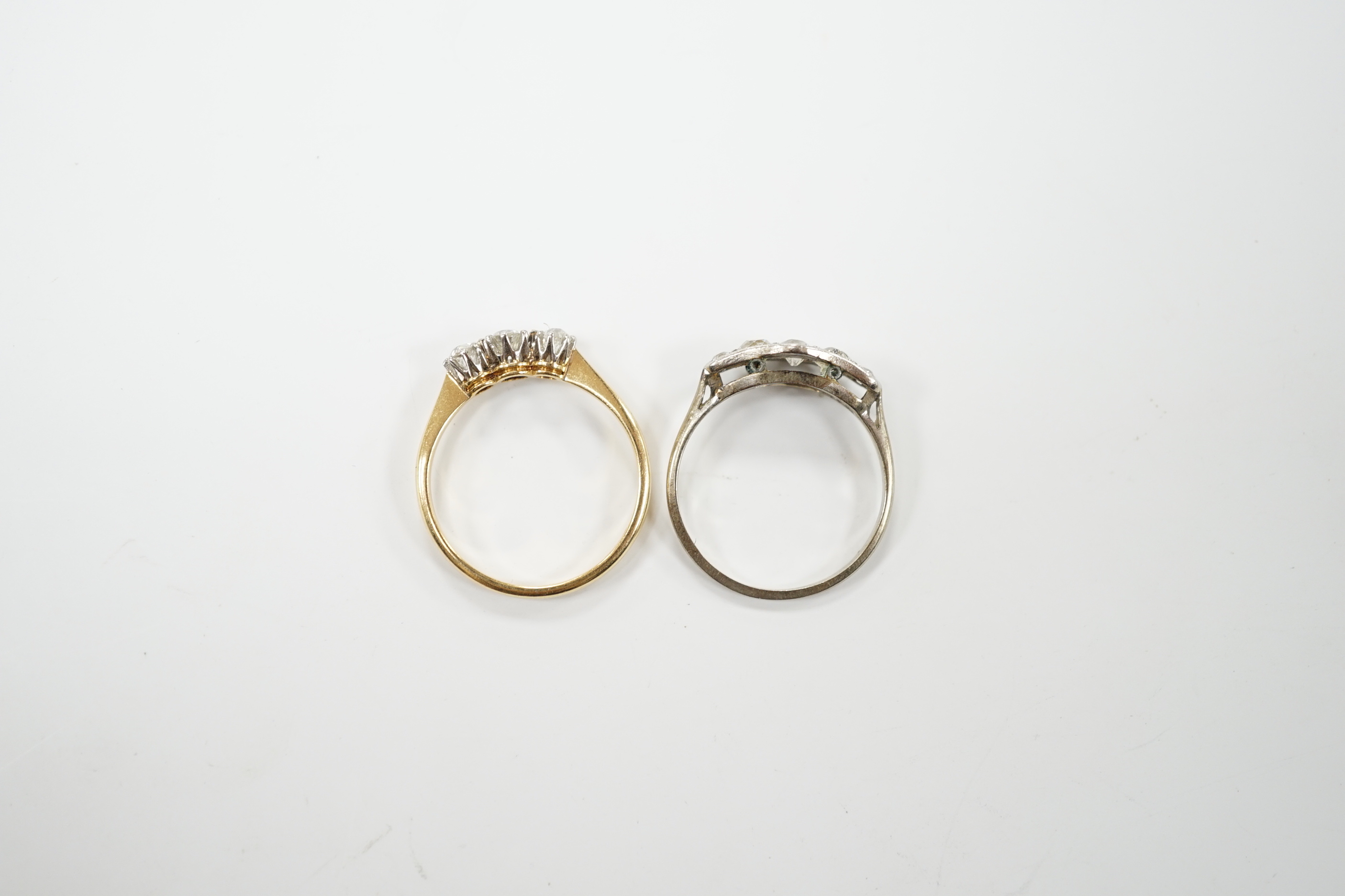 An 18ct gold three stone diamond ring, size M and a white metal five stone diamond dress ring, size M